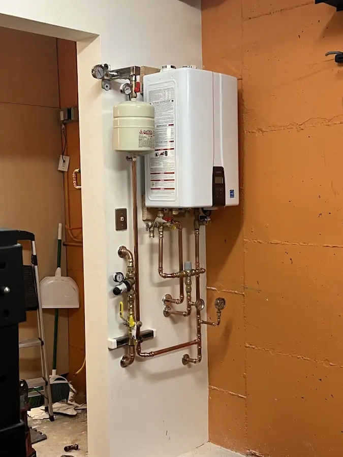 Plumbing technician inspecting water heater connections in Medford